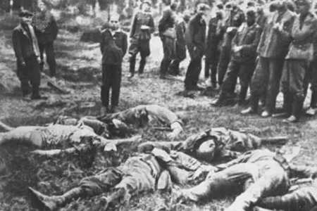 ドイツ国防軍による処刑の前に、家族の死体とともにポーズをとらされた少年（1941年、ウクライナ、ズボロフ）［出典：bund.bindesarchive.de］