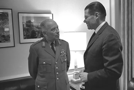 1964 年、ロバート・S・マクナマラ国防長官と会談するホイジンガー［出典: upload.wikimedia.org］