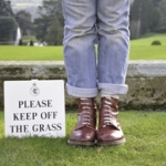 ルールを破る　芝生から出てくださいの注意書きのそばに立つ