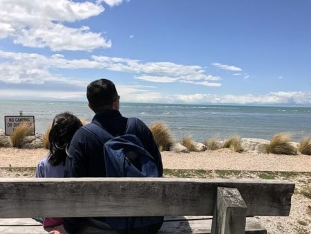 海を眺めるベンチに座った父と娘の後ろ姿